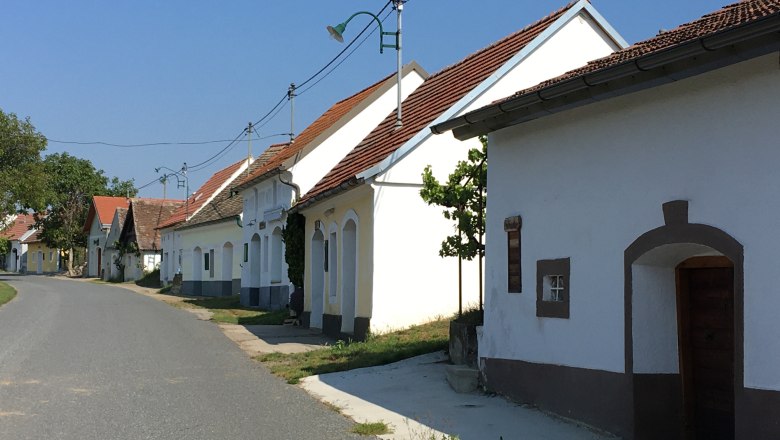 Wine cellar lane Niederschleinz, © Marktgemeinde Sitzendorf A quiet street with traditional whitewashed houses and red roofs in a rural setting.