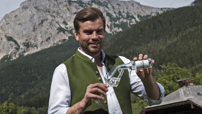 Johannes Ribeiro da Silva at the Riegelhof, © Silva GmbH Man in traditional dress pouring a drink into a glass, with mountain landscape in the background.