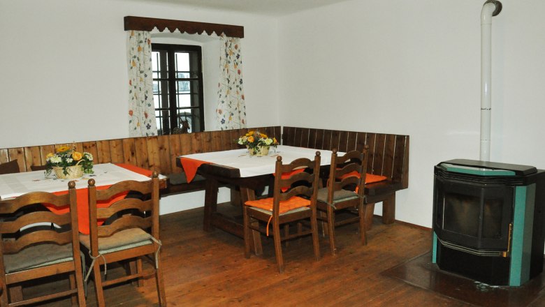Vacation cottage Haltberghof, © Claudia Alber Cozy dining area with wooden table, chairs, corner bench and stove.