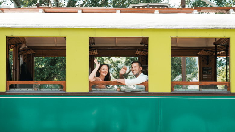 Höllentalbahn, © Österreich Werbung/Stefan Strasser Two people wave from a yellow-green train window.