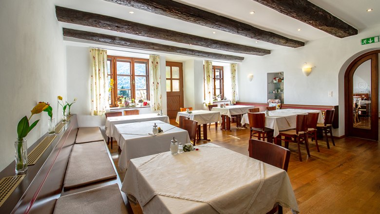 Breakfast room, © Annemarie Heller A cozy breakfast room with wooden beams, laid tables and flowers on the windowsills.