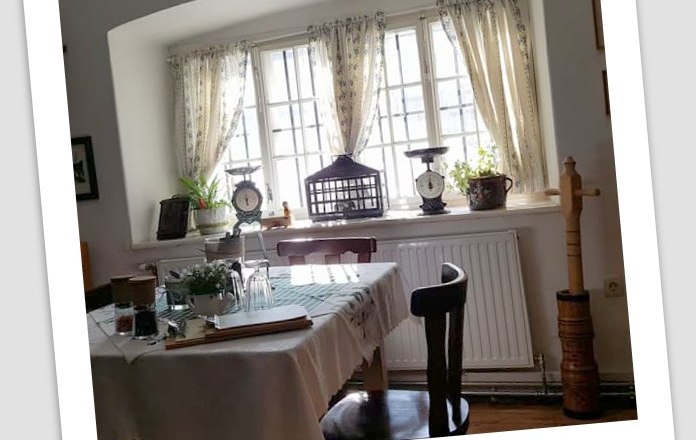 To the forest house, © Waldhaus Cozy dining area with table, chairs and window with curtains.