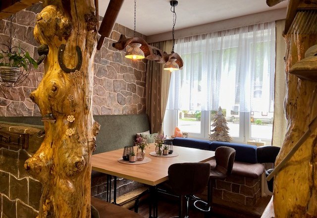 Possibility for cozy hours, © Wiener Alpen Cozy seating area with wooden table, surrounded by rustic wooden elements and stone walls.