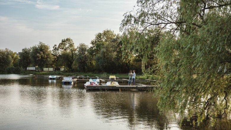 Landscape pond in Bernhardsthal, © Michael Reidinger A quiet pond with boats and a jetty, surrounded by trees.