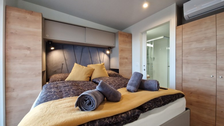 Double bed Johannesbachklamm Chalet, © Johannesbachklamm Chalet Modern bedroom with double bed, yellow pillows and towels, wooden wardrobes and air conditioning.