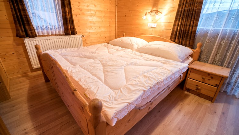 Apartment "Panorama" Bedroom, © Familie Morgenbesser Cozy bedroom with wooden walls, double bed and bedside table in a vacation apartment.