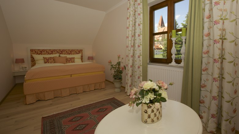 Rose romance, © www.wachaufoto.at Cozy bedroom with floral design and view of a church through the window.