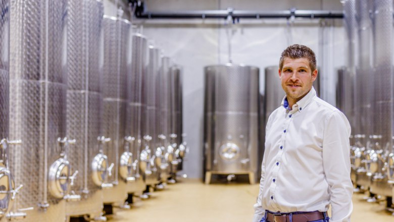 Mathias in his kingdom, © Peter Buchgraber A man stands in a room with large stainless steel tanks.