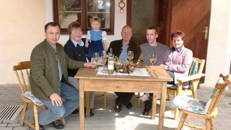 Family business, © Familie Arocker A family is sitting at a wooden table outside drinking wine.