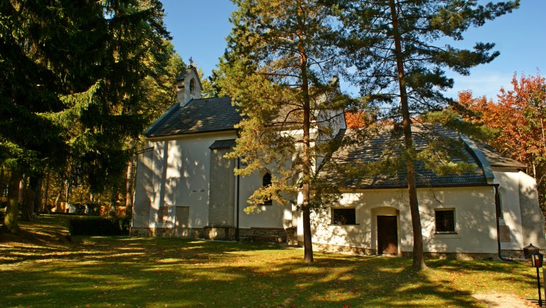 St. Ulrich's Church and the Glass Way of the Cross, © Klaus Hruby A small church in the forest, surrounded by trees and autumn leaves.
