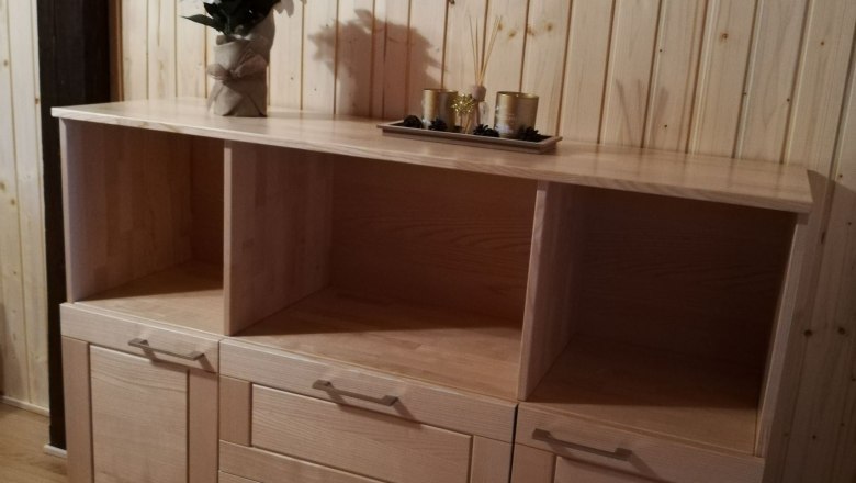 Top floor apartment, © Familie Weibels Wooden chest of drawers with decoration in a room with wood paneling.