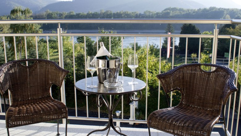 Terrace, © Alexander Pfeffel Two rattan chairs and a table with a champagne cooler on a terrace with a mountain view.