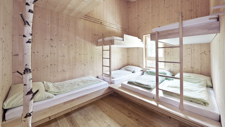 Multi-bed room in the Naturfreundehaus Knofeleben, © Wiener Alpen / Bene Croy Multi-bed room with wooden paneling and bunk beds in the Naturfreundehaus Knofeleben.