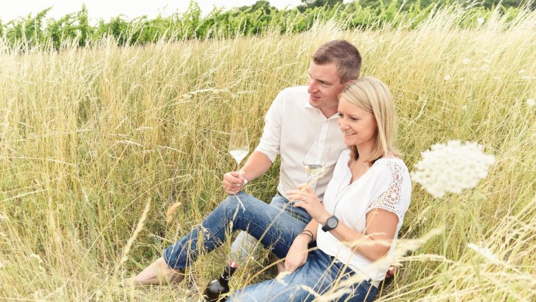 Wagner Winery, © Weingut Wagner A couple sits in the tall grass and drinks wine.