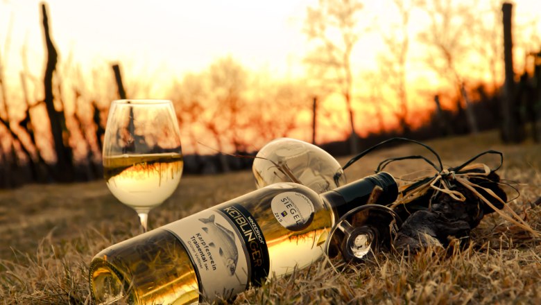 Wine from Winzerhof Keiblinger, © Winzerhof Keiblinger Wine bottle and glass in the grass at sunset.