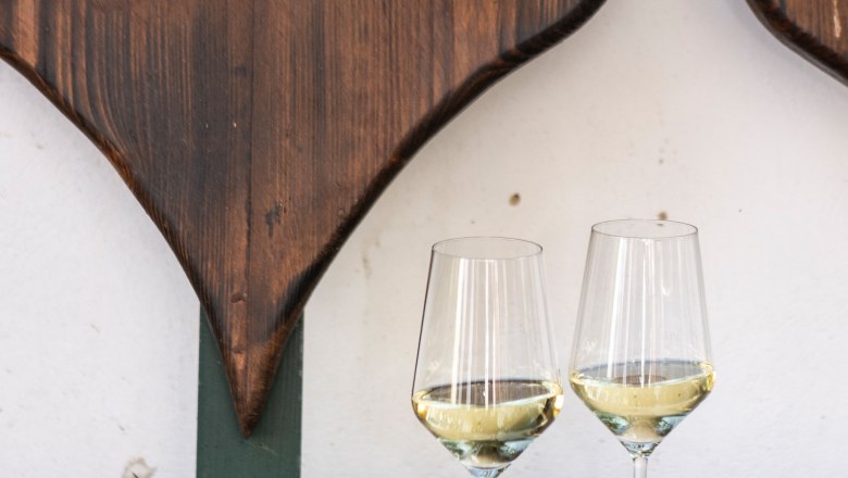 Wine glasses, © Weinviertel Tourismus / Doris Schwarz-König Two wine glasses with white wine on a wooden table in front of a heart-shaped wooden decoration.