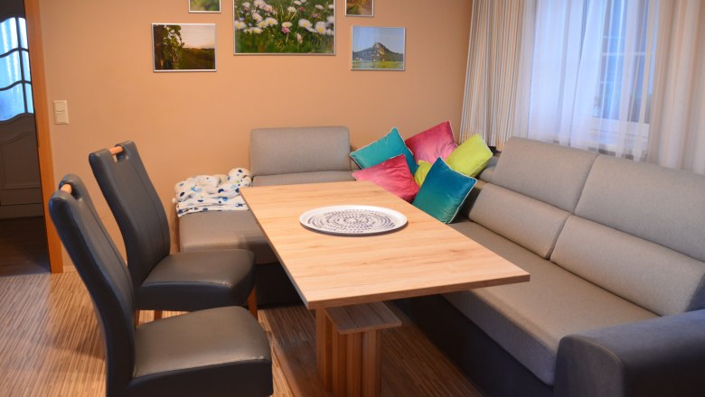 Living and dining area, © Eva Stuhr Living and dining area with grey sofa, wooden table, colorful cushions and murals.