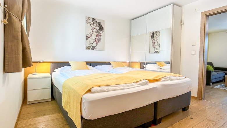 House Morning Sun Bedroom, © Fam. Pauker Modern bedroom with double bed, yellow comforter and large closet with mirrors.