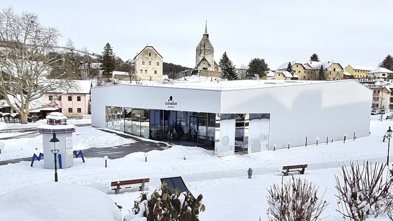 Sconarium in winter, © Wiener Alpen Modern building in the snow with a church in the background.