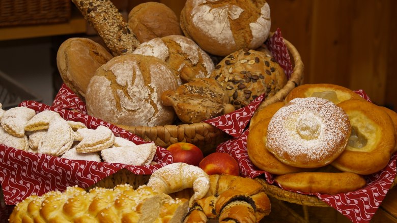Fresh from the oven, © Oberaigner Various breads and pastries on a table, decorated with red cloths.