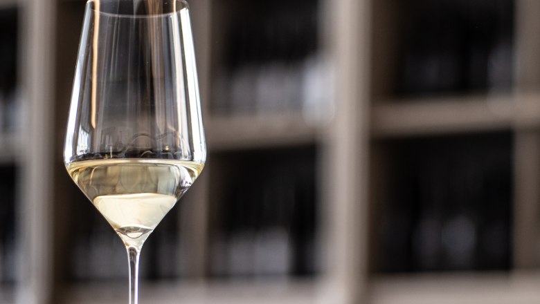 Wine glass, © Weinviertel Tourismus / Doris Schwarz-König Close-up of a wine glass with white wine in front of a blurred background.