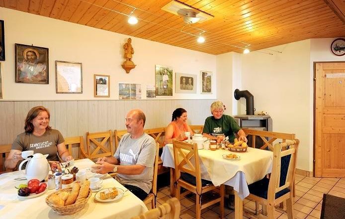Breakfast room, © Steve Haider People have breakfast in a cozy room with wooden furniture and decorations on the wall.