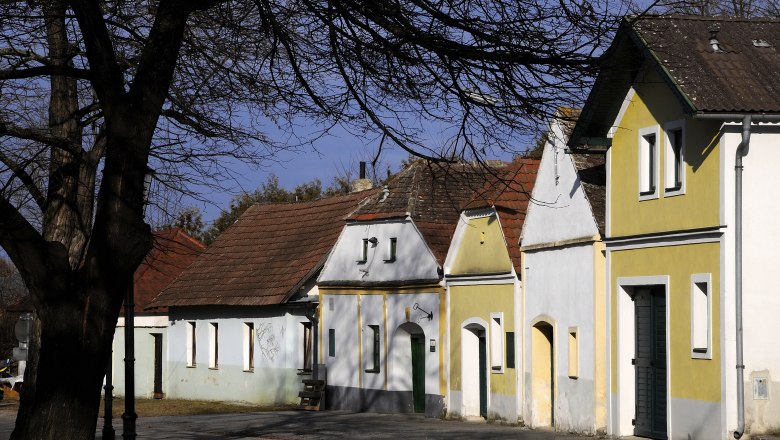 Wine cellar lane Nappersdorf, © Weinviertel Tourismus / Mandl A row of traditional wine cellars in the Nappersdorf wine cellar lane, surrounded by bare trees and blue skies.