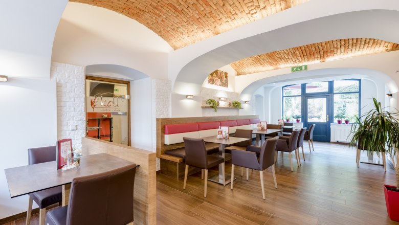 Koll Bistro Kirchschlag, © Koll GmbH Interior view of a modern bistro with vaulted brick ceiling, wooden floor and stylish seating areas.