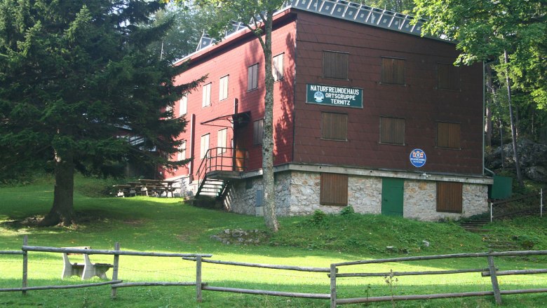 Ternitzerhütte, © WA-Wien A red building with wooden cladding, surrounded by trees and a meadow, with a sign "Naturfreundehaus Ortsgruppe Ternitz".