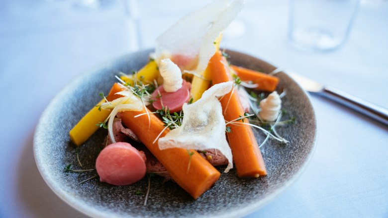 Kitchen line: Waldviertel seasoned with the world, © Niederösterreich Werbung/Daniel Gollner An artfully arranged dish with carrots, radishes and herbs on a gray plate.