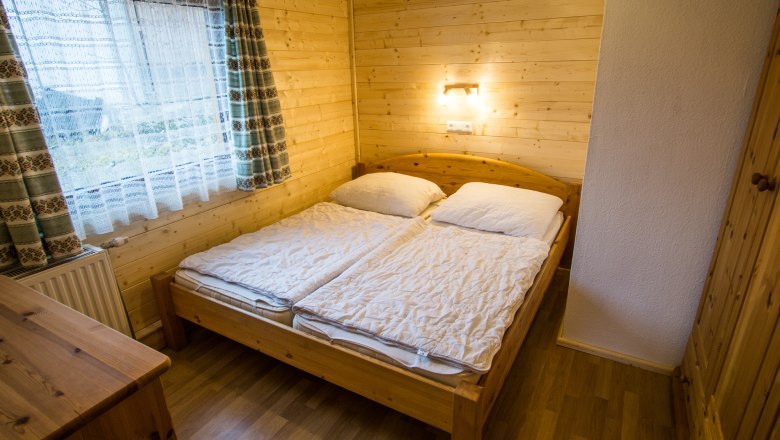 Vacation home "Romantik" Bedroom, © Familie Morgenbesser Cozy bedroom with wooden walls, double bed and window with curtains.
