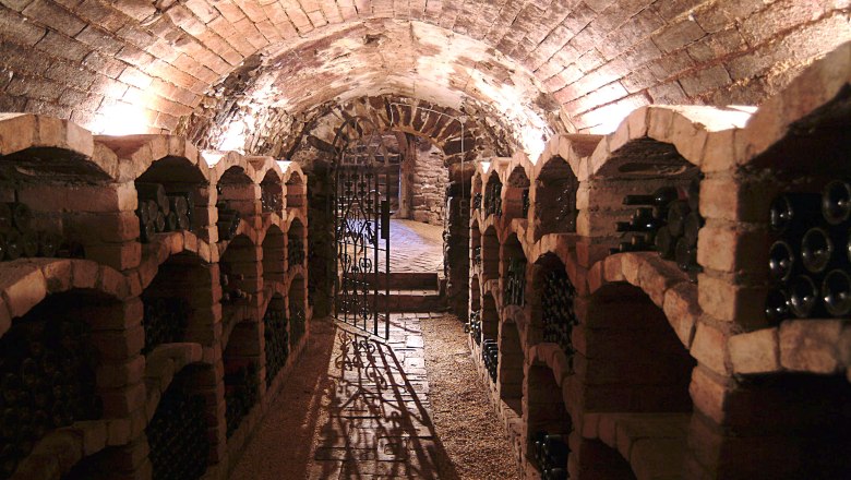 Wine cellar, © Christoph Wurst A wine cellar with brick vaults and wine bottles on shelves.