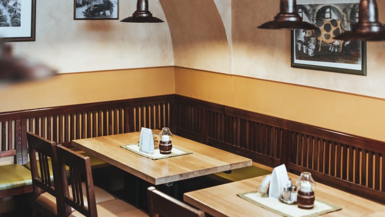 Refreshments in Tulln, © Niederösterreich Werbung/David Schreiber Cozy seating area in a restaurant with wooden tables and chairs, decorated with pictures on the wall.