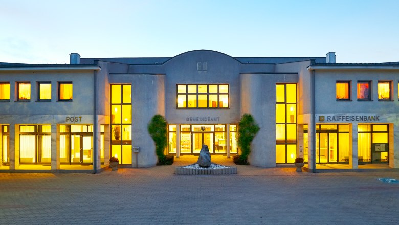 Obritzberg, © zVg Gemeinde Obritzberg-Rust Illuminated building with the inscription 'Gemeindeamt', 'Post' and 'Raiffeisenbank'.