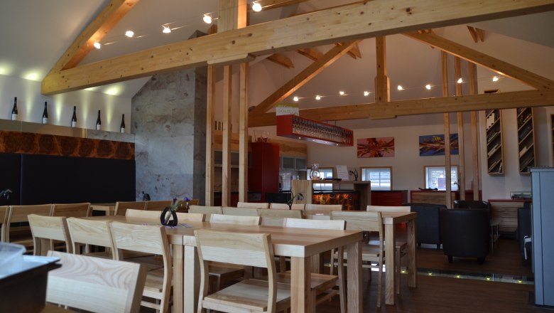 Viticulture Müllner, © Michael Müllner Interior view of a modern winery with wooden beams, tables and chairs.