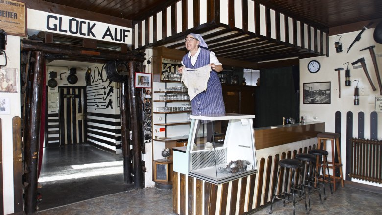 Grünbach Mining Museum, © Wiener Alpen, Foto: Bene Croy Interior view of the Grünbach Mining Museum with a person in traditional clothing standing on a counter.