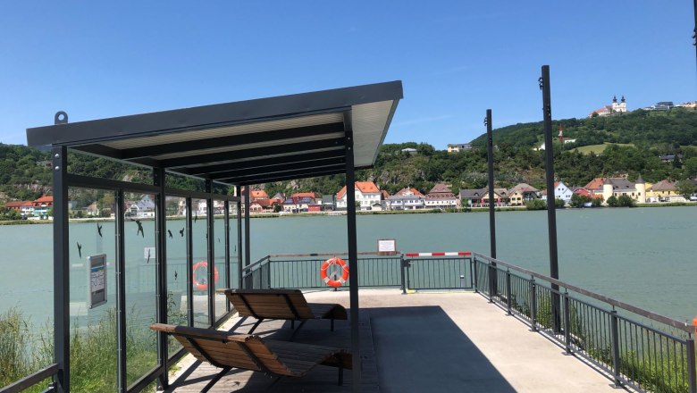 Krummnussbaum landing stage opposite the Maria Taferl basilica, © Donau NÖ Tourismus Mooring with canopy and loungers, river in the background, basilica on a hill.