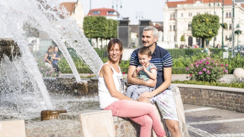 Tulln main square, © Stadtgemeinde Tulln/Robert Herbst A smiling family sits by a fountain on Tulln's main square.