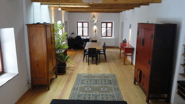 Gillausklause 3, © Stephanus Domanig A stylishly furnished room with wooden floor, wooden beamed ceiling, antique furniture and a carpet.