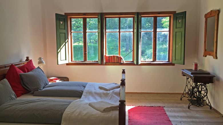 Double room, © Riegelhof Cozy double room with wooden floor, bed, window with green shutters and a red carpet.