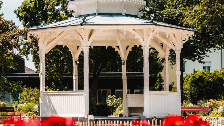 City park pavilion, © Busy Shutters White pavilion in front of blooming red flowers
