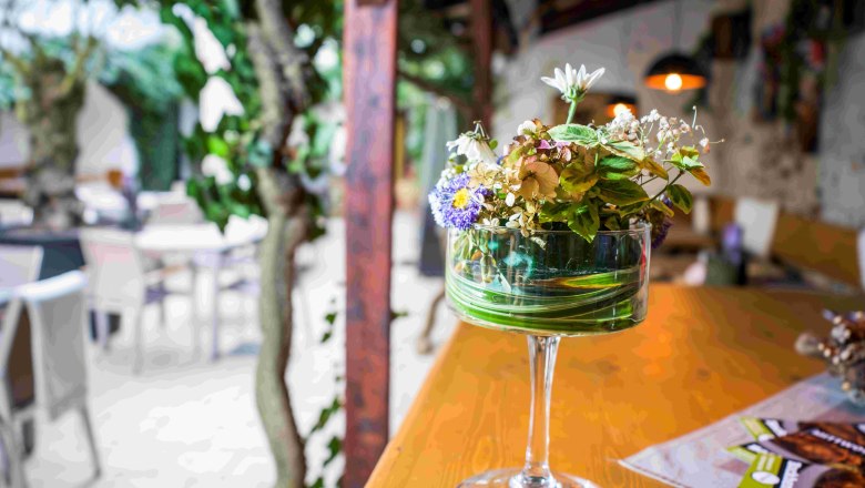 Floral decoration, © Robert Herbst Flower decoration in a glass jar on a wooden table in a café.