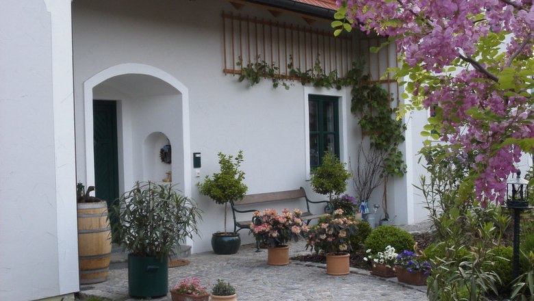 Country house Rossatz, © Landhaus Rossatz Entrance to a country house with flowering plants and a barrel.