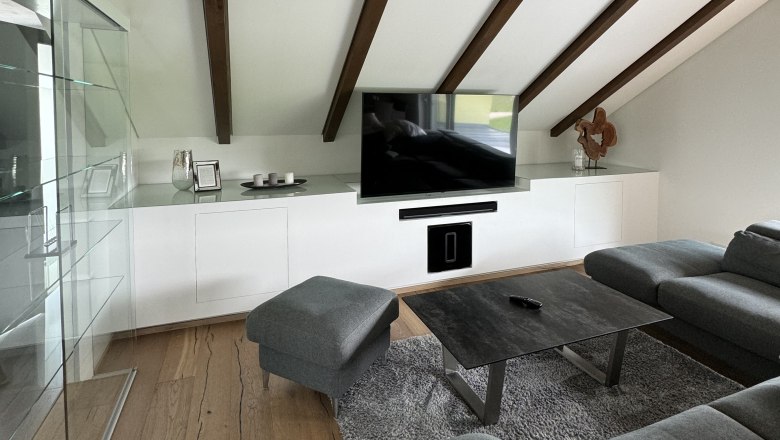 Cozy living area, © Juwel am Stadtrand Modern living area with gray sofa, wooden beamed ceiling and flat screen TV.