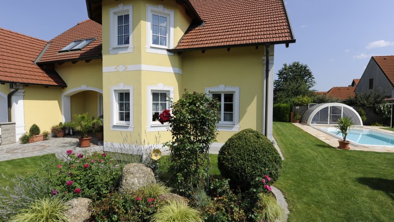 Guest house, © Trachsler Yellow guest house with red roof, garden and pool.