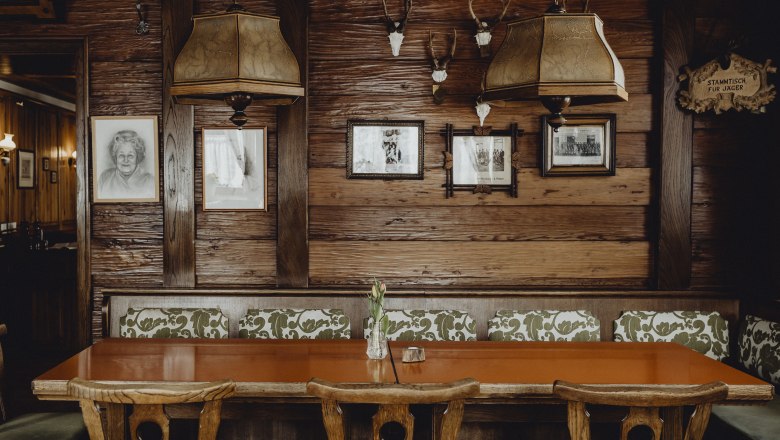 Cozy pub parlor, © Niederösterreich Werbung/Sophie Menegaldo Cozy tavern parlor with wooden table, chairs and rustic decoration on the wall.