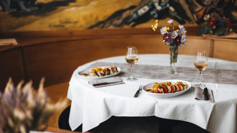 Inn is known for game specialties, © Niederösterreich Werbung/David Schreiber Set table in an inn with two plates and wine glasses.