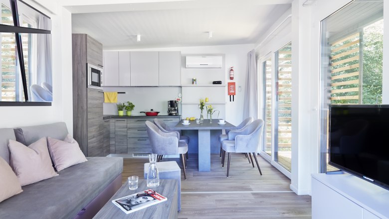 Mobile home interior, © Camping Tulln Mobile home interior with light-colored furniture and eat-in kitchen