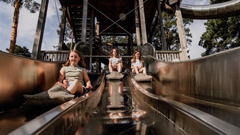 Kittenberg adventure gardens, © Matthias Streibel Three children slide down a metal slide in a park.
