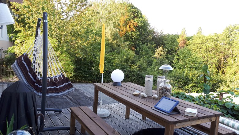 Terrace relax, © DB Terrace with hammock, wooden table and view of green trees.